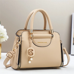 Close-up of beige lychee grain leather handbag featuring a gold star and moon pendant charm