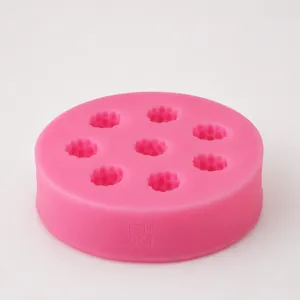 Pink silicone raspberry fondant mold with multiple cavities on a rustic wooden background