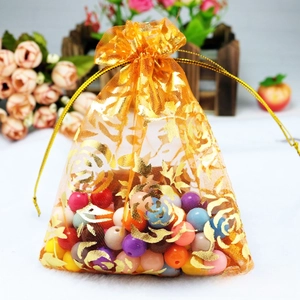 Close-up of golden organza drawstring gift bag featuring elegant gold rose floral patterns