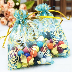 Detail of lake blue organza drawstring gift bag with gold rose pattern and beads