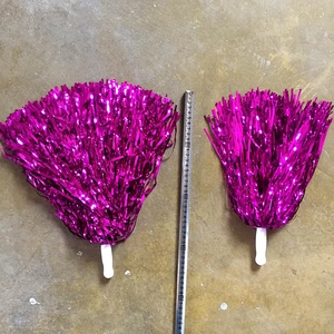 Comparison of two rose red cheerleading pom poms in different sizes with measuring tape