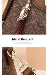 Detail of brown leather handbag with golden cat charm and metallic hardware