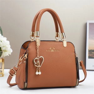 Detailed macro of brown lychee grain PU handbag with gold heart and pearl charm