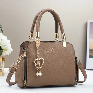 Macro detail of brown lychee grain leather handbag with gold heart pearl charm