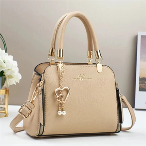 Detail of beige lychee texture leather bag with pearl heart charm and gold hardware