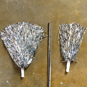Detail van zilveren metallic cheerleading pompons met witte handgrepen en maatvergelijking