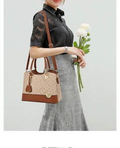 Close-up of beige monogram handbag with brown leather straps and metal logo tag