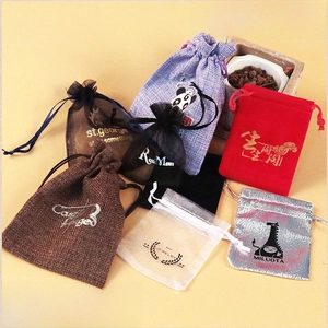 Detail of custom drawstring pouches in burlap, velvet, and organza with gold foil logos