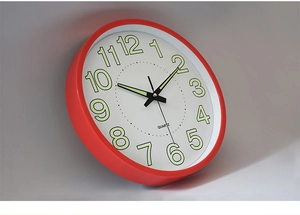Close-up of red metal luminous wall clock with quiet quartz movement and clear 1-12 numerals