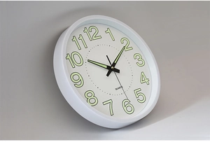 Close-up of white luminous wall clock with quartz movement and large Arabic numerals