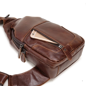 Detail view of the brown leather chest bag showing the front zipper pocket and stitching