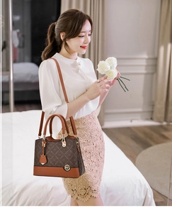 Detail of a brown monogram crossbody bag with leather handles and gold metal hardware