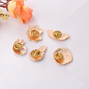 Close-up of golden metal enamel pins set with butterfly clasps and cute fruit shapes