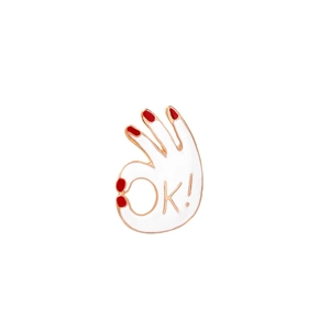 Detail of hand-shaped enamel brooch with OK sign and gold metal trim on white background