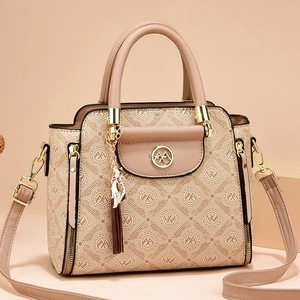 Elegant beige monogram handbag with gold cat charm and adjustable crossbody shoulder strap