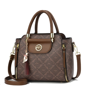 Elegant brown monogram shoulder bag with cat tassel and gold hardware on white backdrop