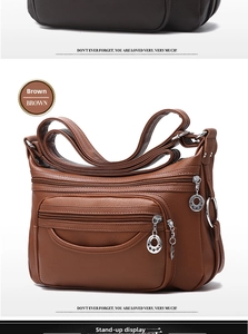 Detail of brown faux leather shoulder bag featuring multiple zippered pockets and star pulls