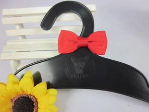 Detail of red grosgrain bow tie on a black plastic pet hanger with a dog logo