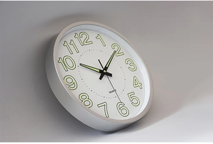 Close-up of modern aluminum wall clock featuring luminous numbers and quartz movement