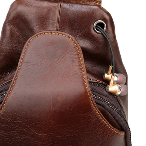 Detailed view of functional earphone port on dark brown genuine leather men's chest bag