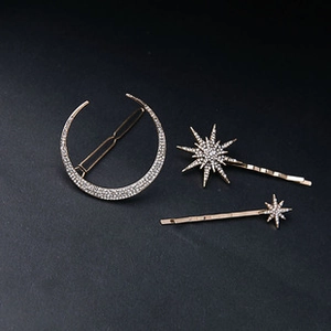 Detailed close-up of 3-piece gold moon and star hair clips with inlaid rhinestones