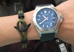 Close-up of olive green paracord bracelet with matte black metal anchor clasp on wrist