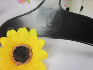 Detailed close-up of a black dog-paw shaped plastic hanger for pet clothes with logo detail