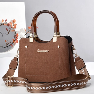 Detail of canvas texture shoulder bag with wood-style handle and patterned strap