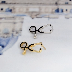 Macro view of stethoscope earrings in gold and silver finishes with black enamel