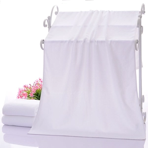 Close-up of fluffy white hotel bath towels hanging and folded on a minimalist white rack