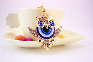 Détail du porte-clés hibou avec perles œil bleu et strass brillants sur métal doré