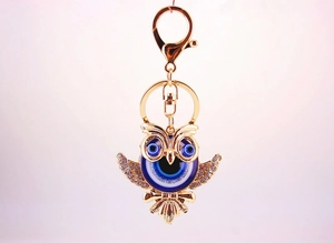 Détail d'un porte-clés chouette doré avec cristaux et breloques œil bleu protecteur