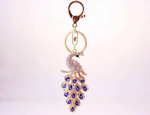 Pfau-Schlüsselanhänger in Gold mit blauen Evil Eye Federn und Kristallbesatz