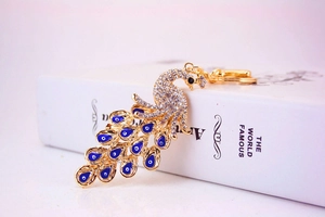 Detailansicht eines Pfau-Schlüsselanhängers mit goldener Basis und glänzenden Strass