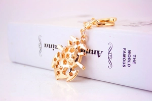 Detailed close-up of a gold metal beetle keychain with an intricate hollow-out pattern