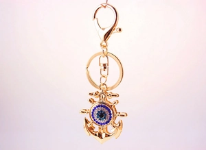 Close-up of golden anchor keychain with blue evil eye charm and crystal rhinestones