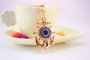 Close-up of golden anchor keychain featuring a blue evil eye with sparkling crystals