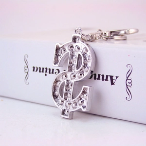 Silver dollar sign keychain with sparkling crystals and standard ring on a book