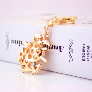 Gold anchor and crab keychain with intricate hollow patterns on a white book