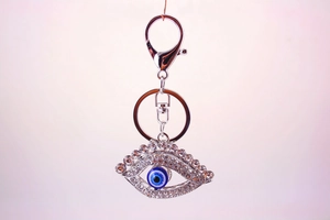Dettaglio portachiavi argento con malocchio blu, strass e anello a molla lucido