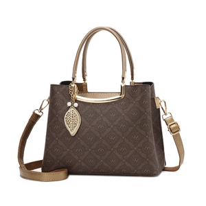 Bolso de mano marrón con monograma para mujer con colgante de hoja dorada y detalle de perla