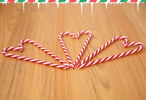 Red and white striped candy canes arranged in heart shapes on a warm wooden background