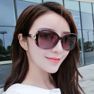 Detail of oversized sunglasses featuring purple gradient lenses and gold floral metal accents