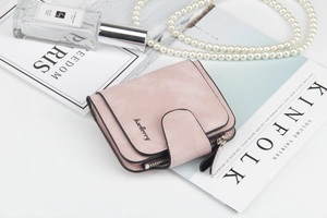 Vista piatta di un portafoglio in pelle rosa opaca su riviste di moda con accessori