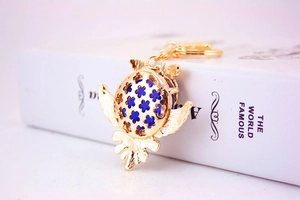 Vue macro d'un porte-clés chouette doré avec motifs de fleurs et pierre précieuse bleu foncé