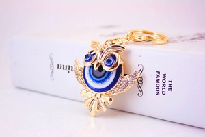 Détail du porte-clés chouette doré avec strass et motif œil protecteur bleu brillant