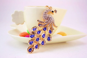 Detail eines goldenen Pfau-Schlüsselanhängers mit Strass und blauen Evil Eye Anhängern