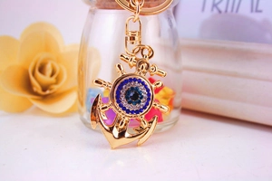 Close-up of golden anchor keychain with blue crystal evil eye and sparkling rhinestones