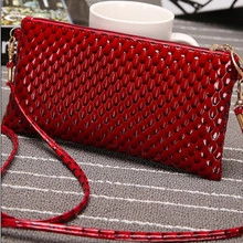 Detailed view of red rectangular patent leather crossbody bag with crocodile texture