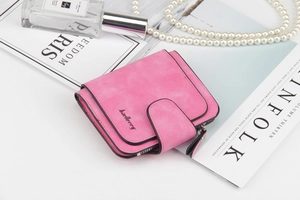 Piccolo portafoglio rosa in ecopelle con fibbia e cerniera su uno sfondo di moda